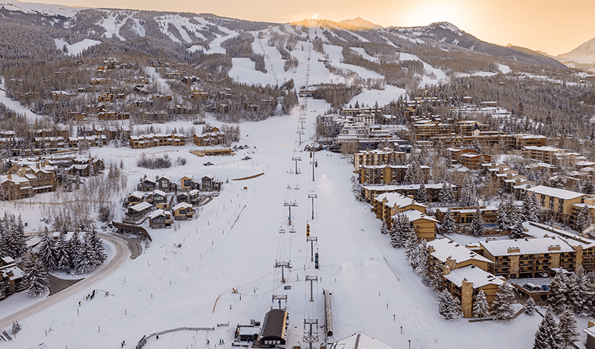 Sunsets over the base of Snowmass, the village is illuminated below the orange sunset